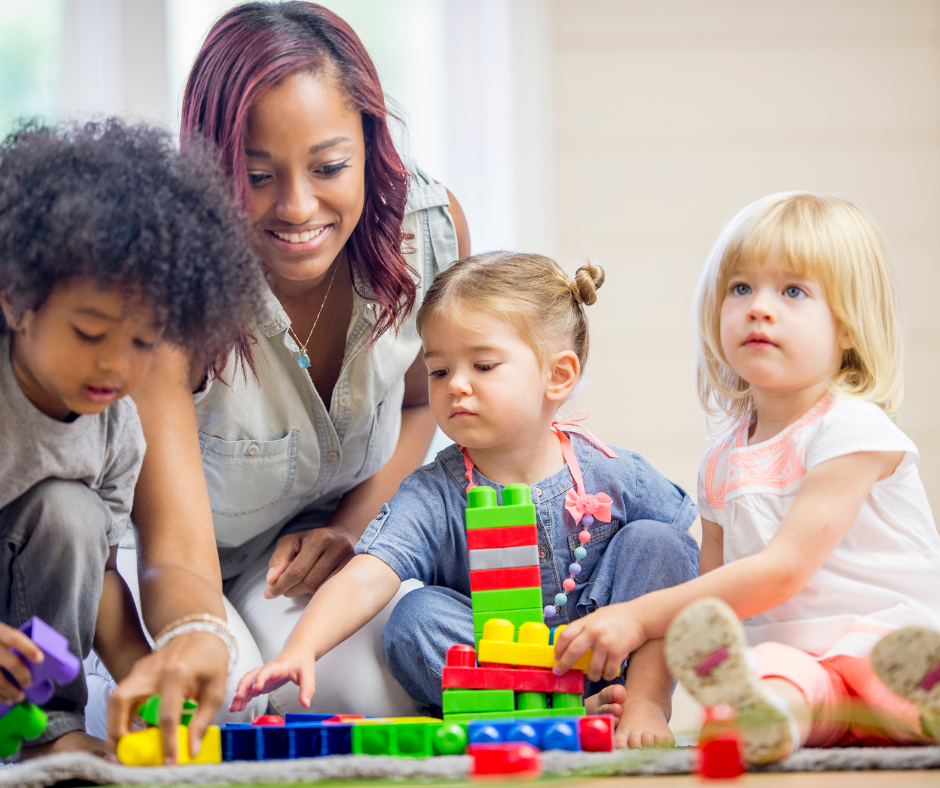 practitioner with nursery children constructing with bllocks