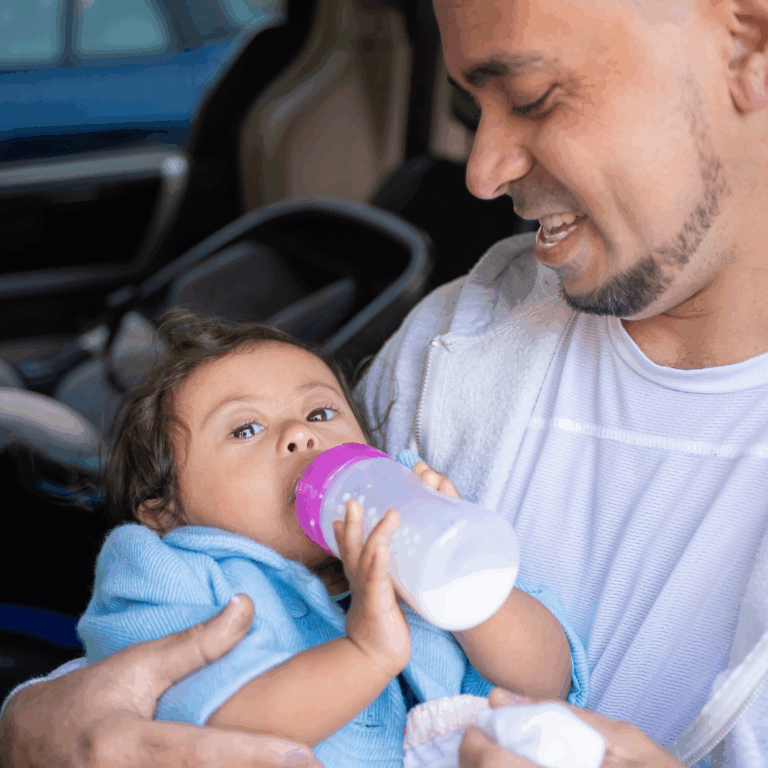 A man nurturing a baby and feeding it a bottle of milk