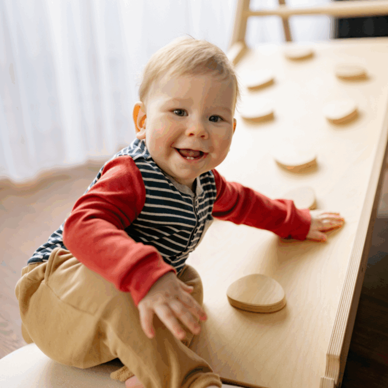 An image of a toddler climbing some apparatus and smiling in a preschool setting