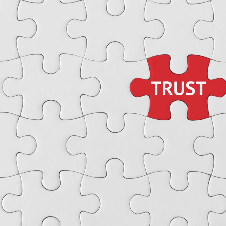 An image of a white jigsaw puzzle with one red piece in red with the word trust written on it.