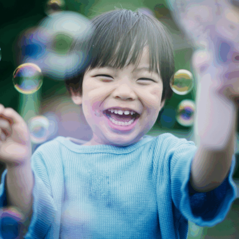 A smiling child blowing bubbles