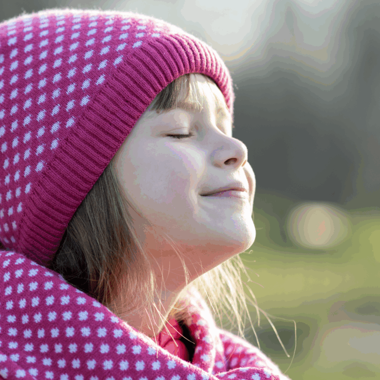 Child smiling with closed eyes breathing the fresh air and feeling calm