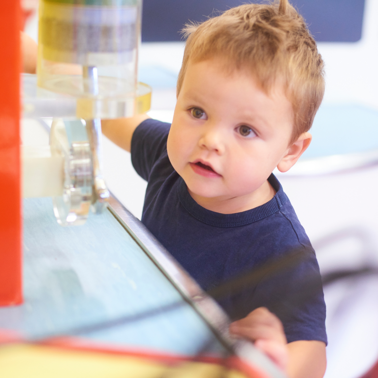 A child looking with curiosity at some plastic wheels and tubes