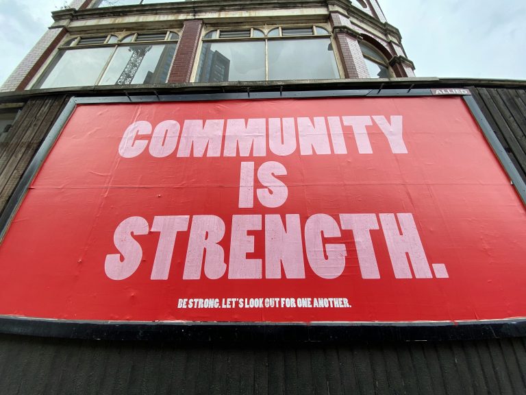 An image of a billboard saying "Community is strength"