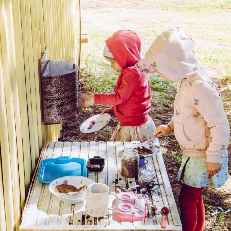 2 Preschoolers exploring the mud kitchen in the outdoor provision at nursery