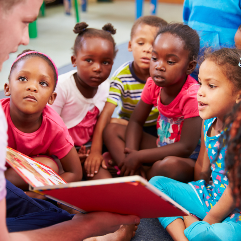 A group of preschoolers with a practitioner sharing a book