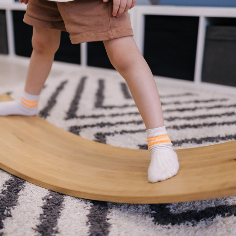 An image of a preschooler balancing on a wobble board