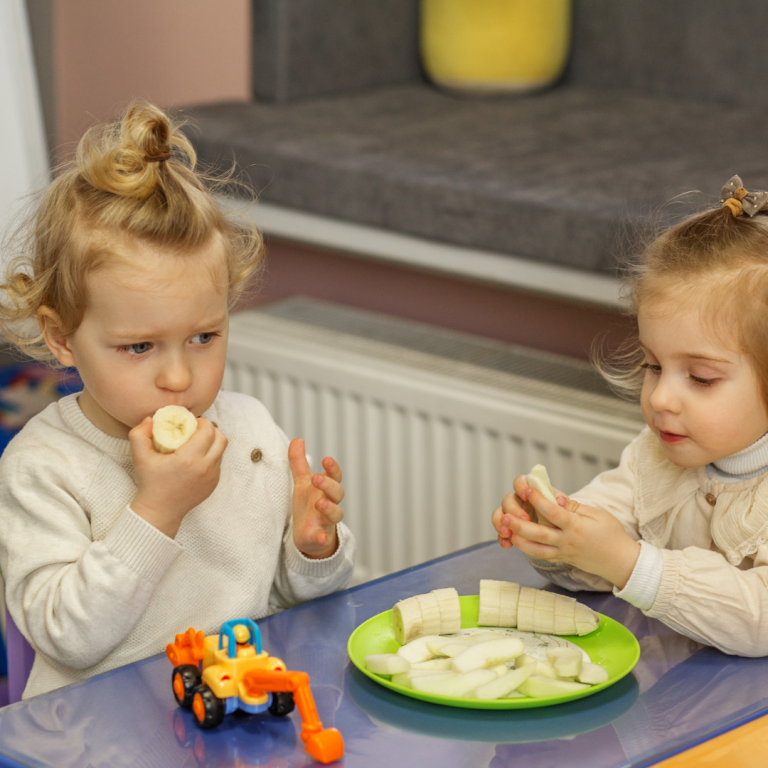 Snack time - 2 preschoolers at a table eating fruit