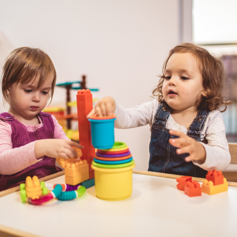 Preschoolers placing plastic containers inside each other as the size of container gets smaller