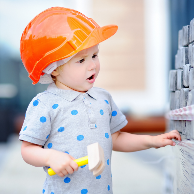 Preschooler dressed as a builder making a wall