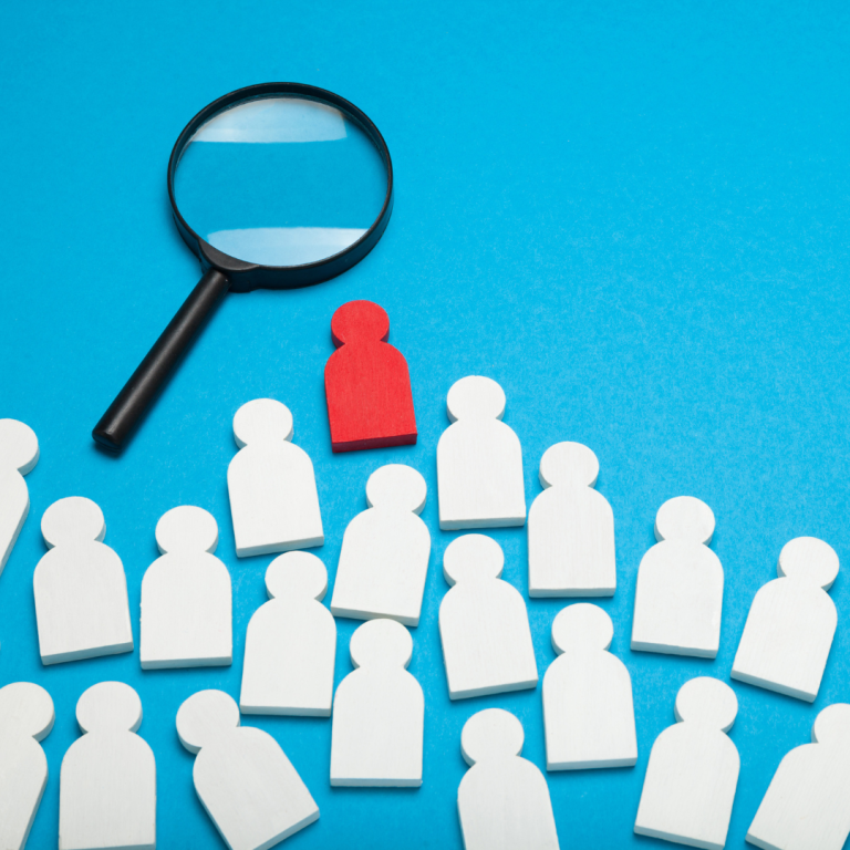 A graphic of people shapes with one in red under a magnifying glass