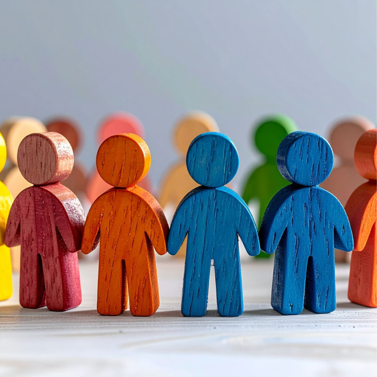An image of different coloured wooden figures holding hands to represent inclusion