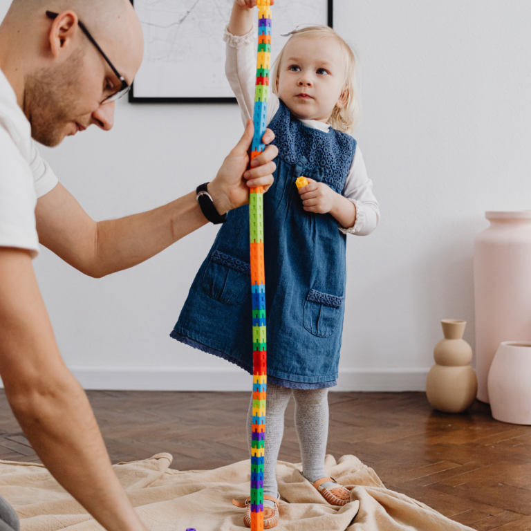 An image of a child and an adult solving the problem of a tower of bricks engaged in sustained shared thinking