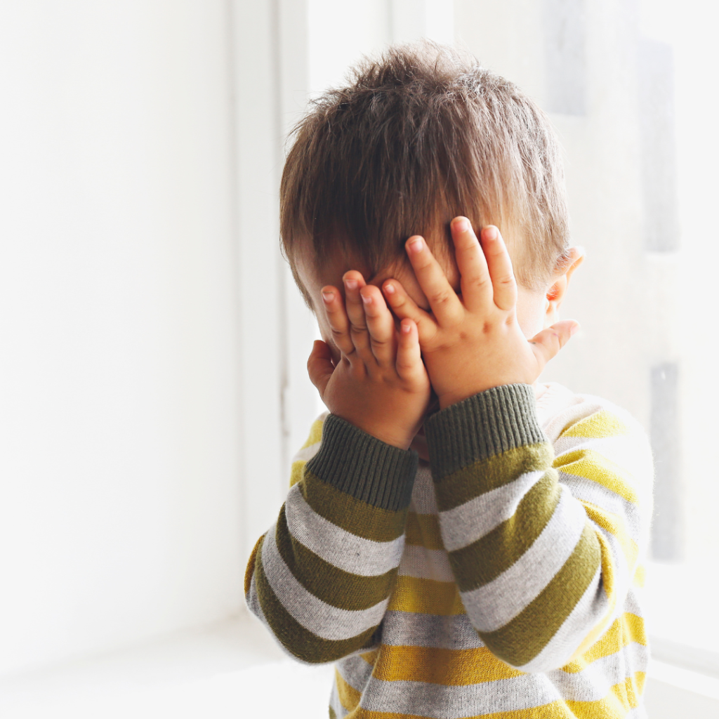 A Toddler struggling to communicate his emotions with hands to his face