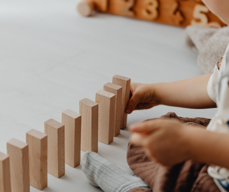 a child lining up wooden blocks to build a wall