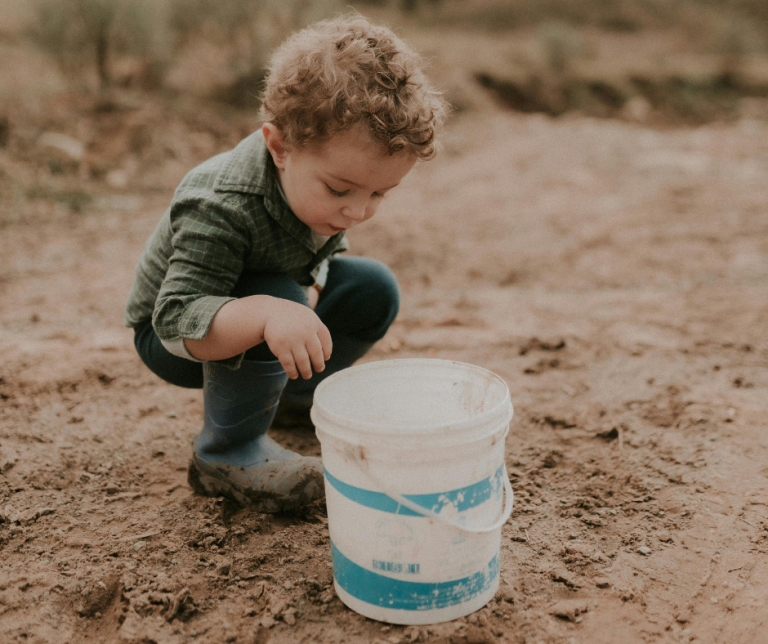 A child exploring with soil and a large bucket
