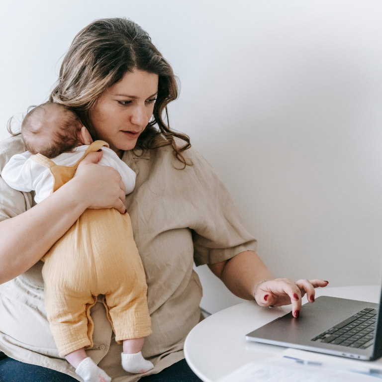 A mum holding her child while filling out online forms