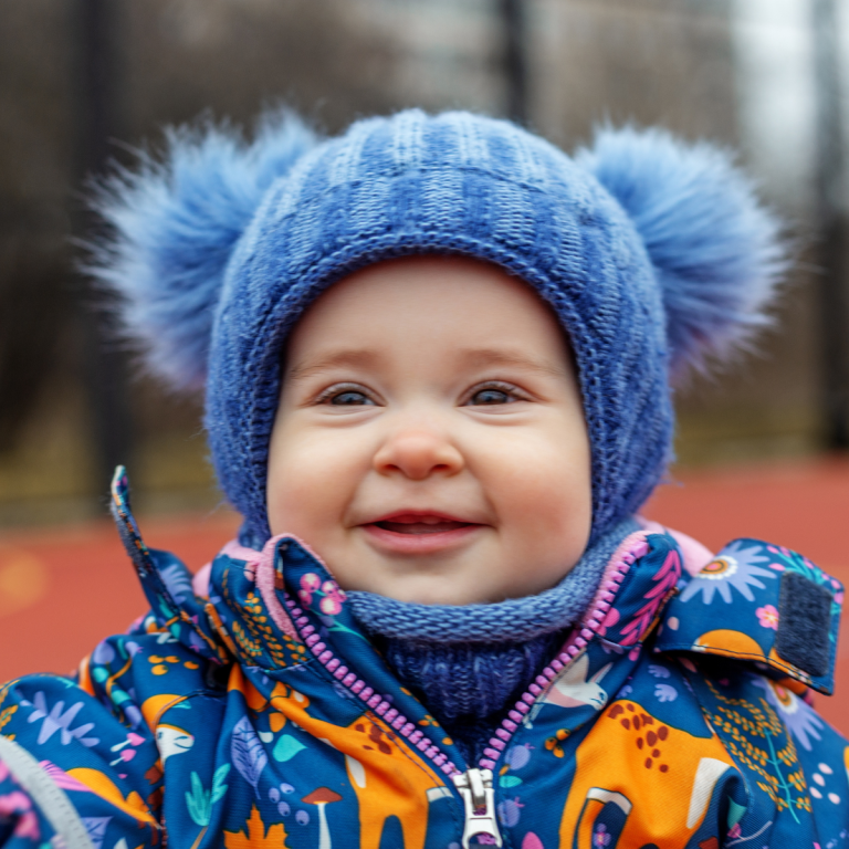 An image of a smiling toddler in a woolly hat